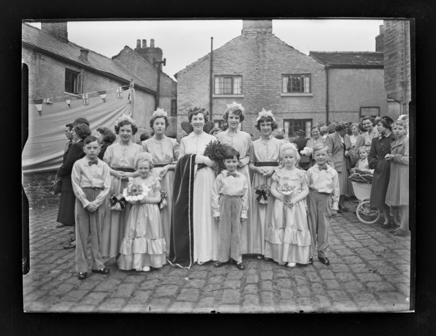 A group picture of boys an gilrs in dresses an smart trousers. The women are wearing floral gowns.